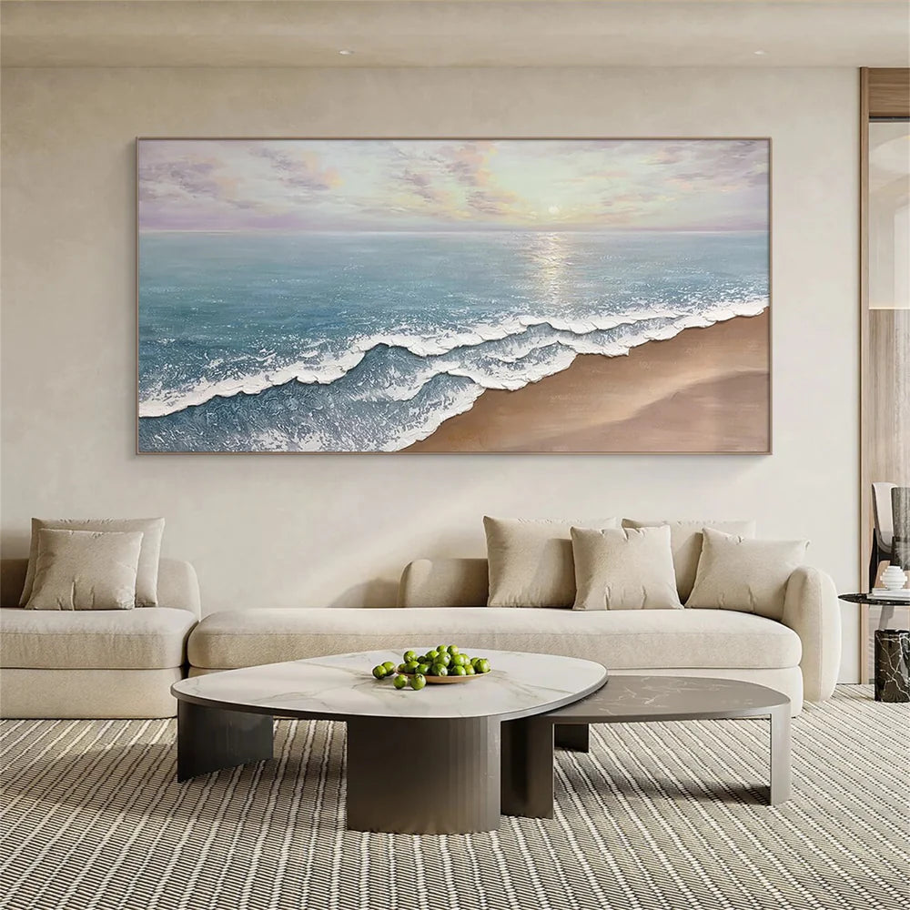 Soft coastal beach painting above neutral living room seating by Wonder Artwork